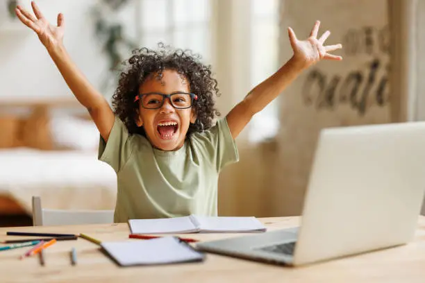Happy child raising hands excited about learning phonics online