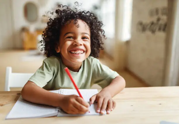 Happy child studying and writing at home learning phonics online